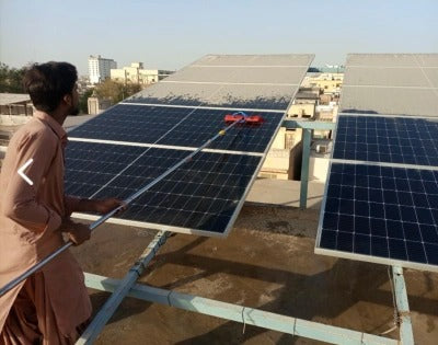 Solar panel cleaning brush being used on rooftop panels